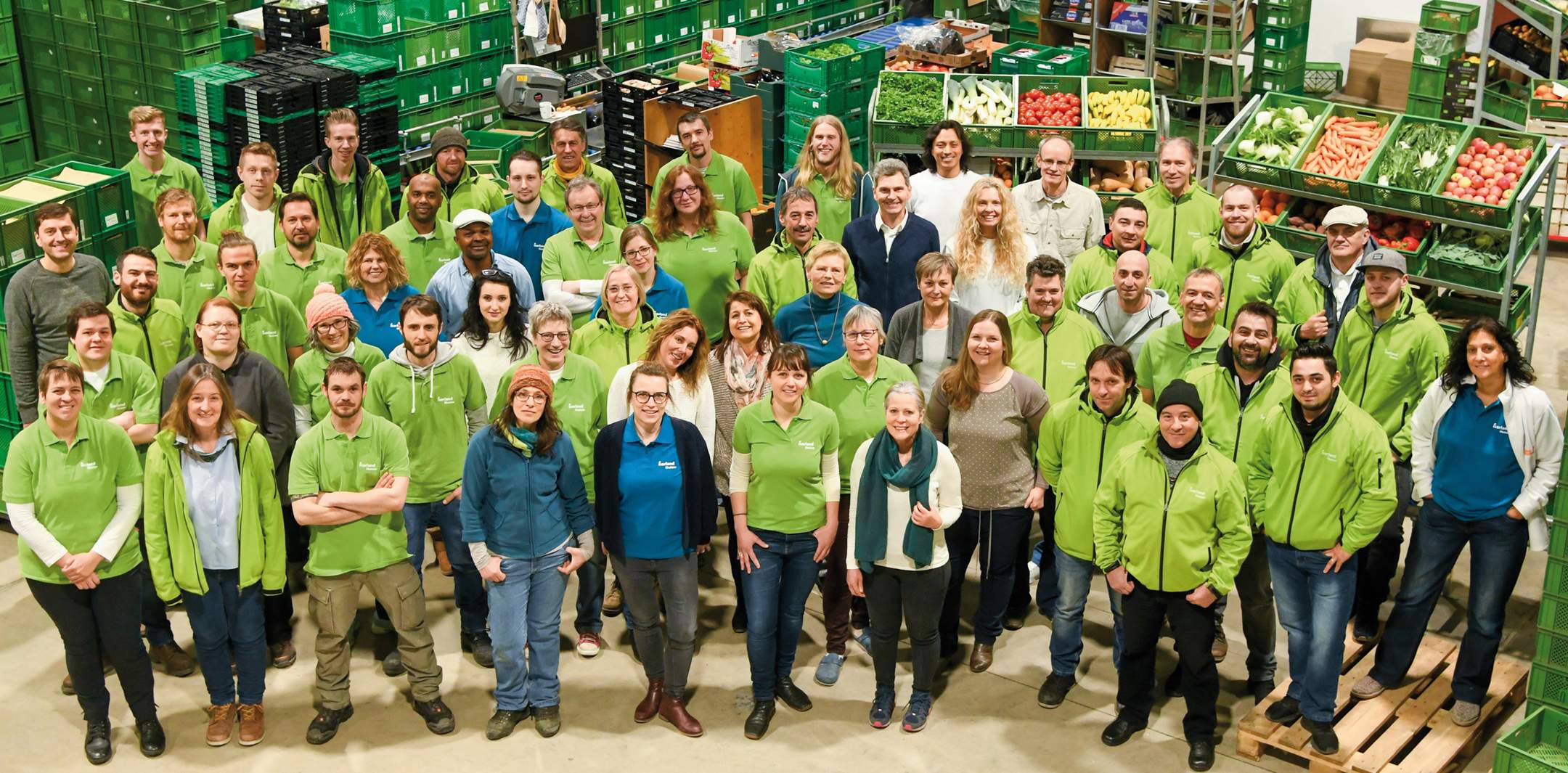 Eine Vielzahl von Isarland Mitarbeitenden steht lächelnd als Gruppe in der Isarland Packhalle.