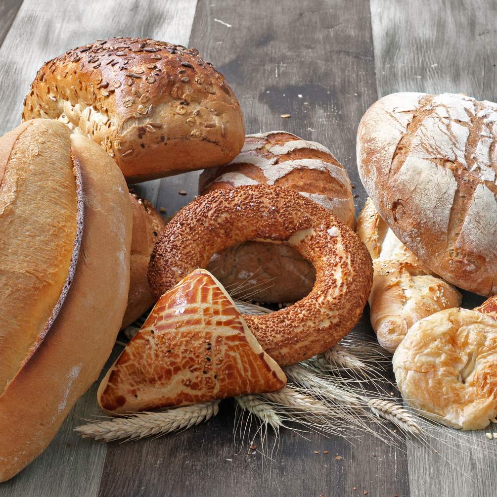 Frische Semmeln, Brote und weitere Gebäckteile auf einem Holztisch.