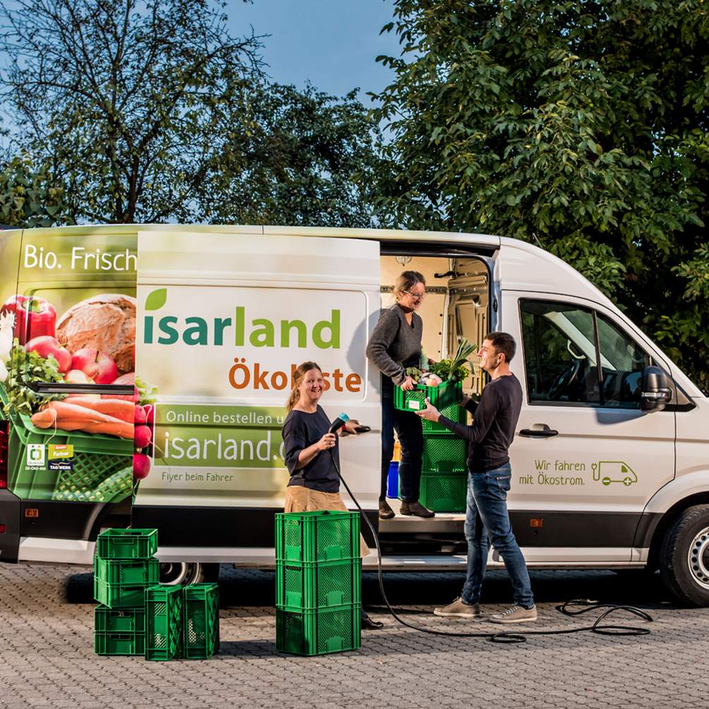 Die drei Geschäftsführenden der Isarland Ökokiste beladen einen E-Lieferwagen.