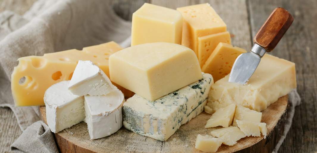 Auf eine Holzplatte angerichtete Käseplatte mit verschiedenen Käsesorten, wie z.B. Weichkäse, Emmentaler und Blauschimmelkäse.
