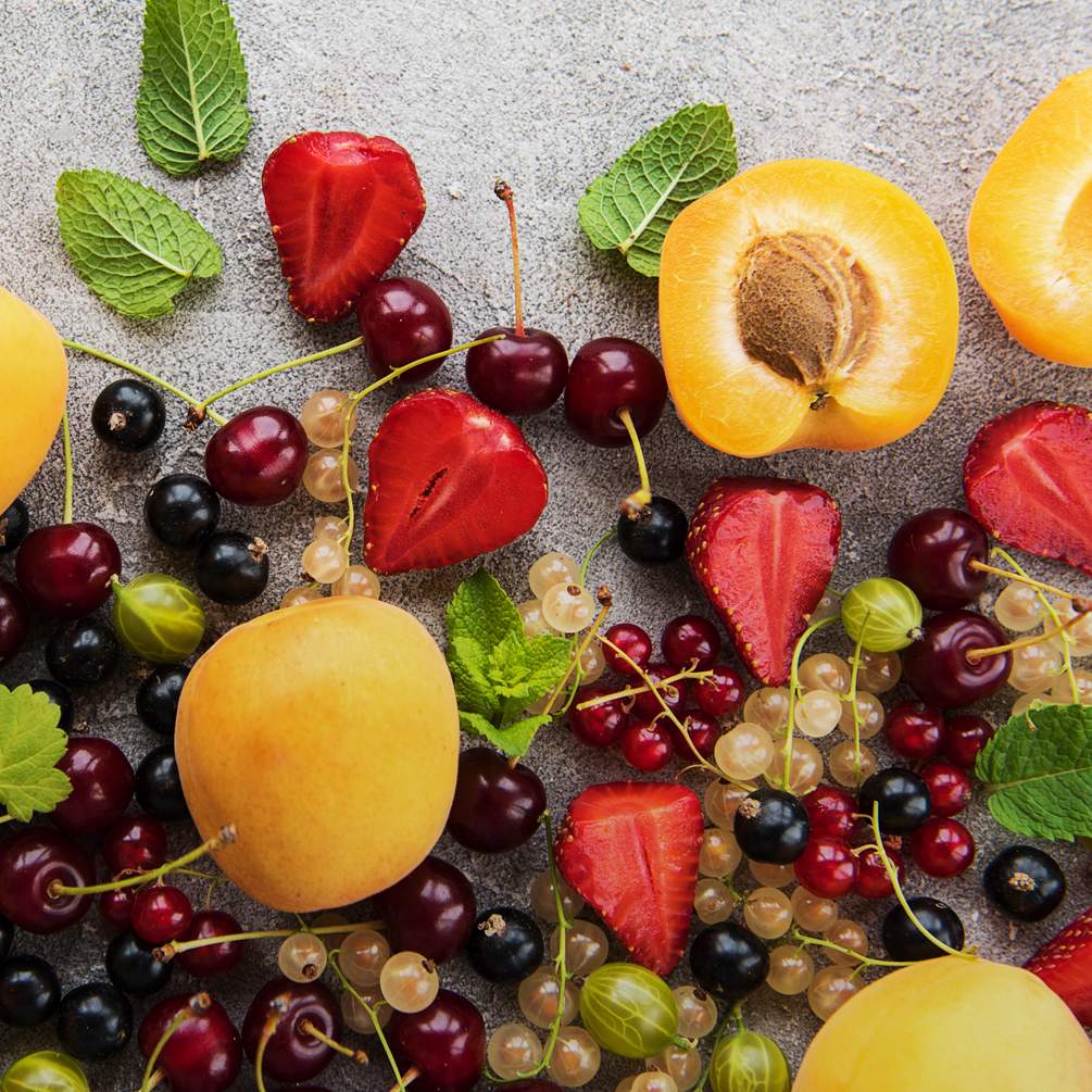 Arrangement mit Sommerfrüchten wie Aprikosen, verschiedene Johannisbeeren, Stachelbeeren und Kirschen.
