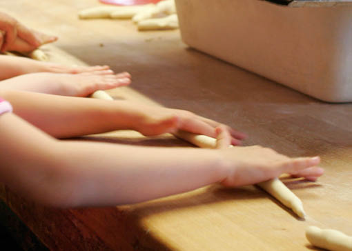 Kinderhände drehen Brezn auf Holzuntergrund