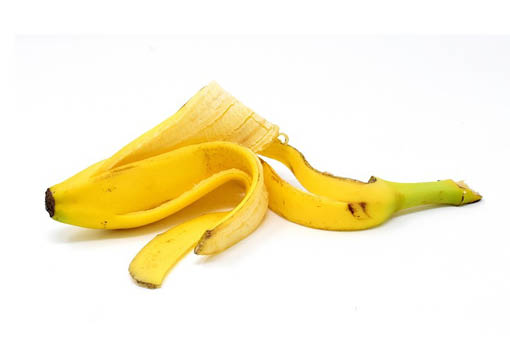 Gelbe Bananenschale auf weißem Untergrund.