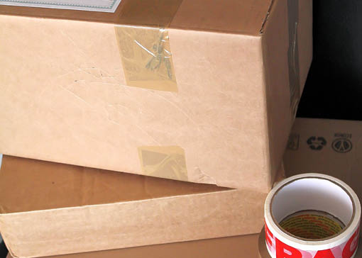 Gestapelte Pappkartons und eine rolle Paketband.
