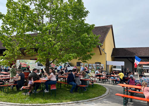 Frau und Kinder sind in einem Kuhstall, in dem der gesamte Boden mit Heu bedeckt ist, neben einer Kuh.