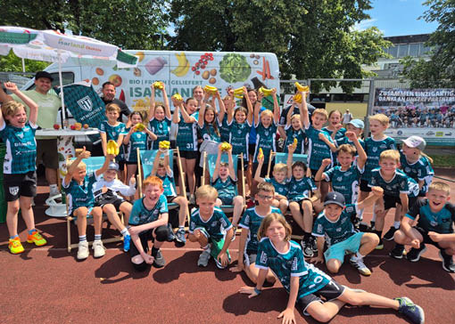 Junge Handballerinnen und Handballer mit Banenen von BioTropic - im Hintergund ein Isarland Lieferwagen.