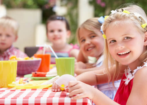 Frau und Kinder sind in einem Kuhstall, in dem der gesamte Boden mit Heu bedeckt ist, neben einer Kuh.