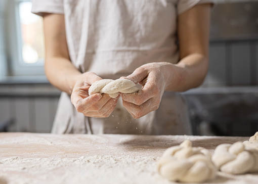 Person knetet und formt Teig über einer mit Mehl bestäubten Platte.