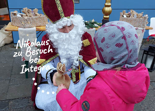 Der Nikolaus übergibt ein Säckchen an ein kleines Kind.