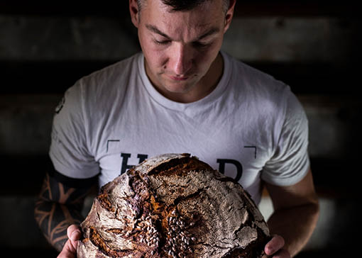 Nico Scheller hält ein Brotlaib in den Händen.