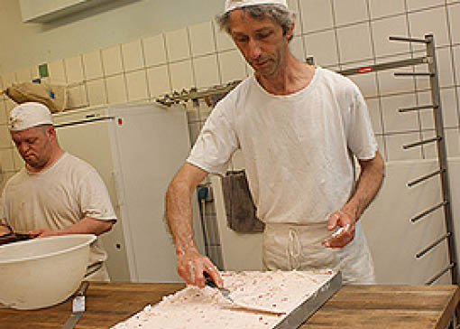 Ein Bäcker verteilt eine Creme auf einem Kuchen.