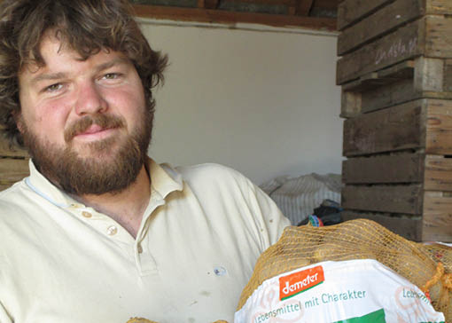 Christoph Knoll steht in einem Lagerraum mit einem Kartoffelsack.