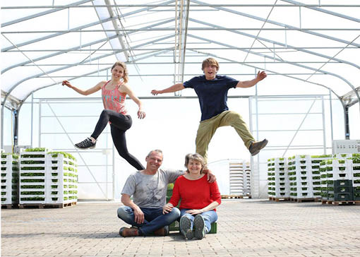 Familie Laurer in ihrer Packhalle, Ehepaar Laurere sitzt auf dem Boden, die Kinder springen in die Luft.