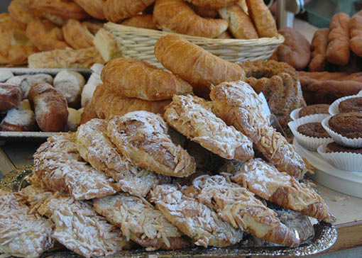 Große Tablettes mit Süßgebäck, wie Mandeldroissants, Croissants und Muffins auf einem Tisch