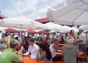 Besucher sitzen an Bierbänken beim Eröffnungsfest der Isarland Ökokiste im Juli 2018