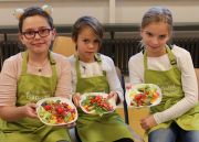 Drei Schülerinnen der Grundschule Taufkirchen am Wald halten Selbstgekochtes in die Kamera.