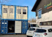 Neben dem Isarland Gebäude stehen Container und E-Wägen.