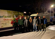 Helferinnen und Helfer stehen nachts vor einem Lieferwagen der Isarland Ökokiste.