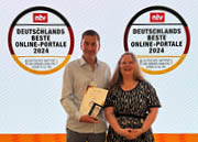 Die Geschäftsführenden Christian Supenkämper und Nicole Göpel halten auf einer Bühne Urkunde und Preis für Deutschlands beste Online-Portale in Händen.