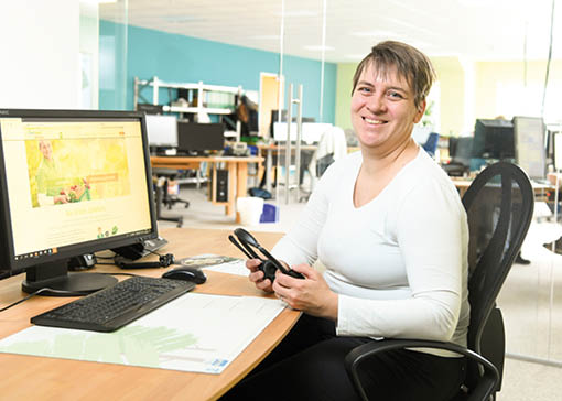 Isarland Kundenservice Mitarbeitende am Schreibtisch mit Headset in der Hand und vor dem Bildschirm.