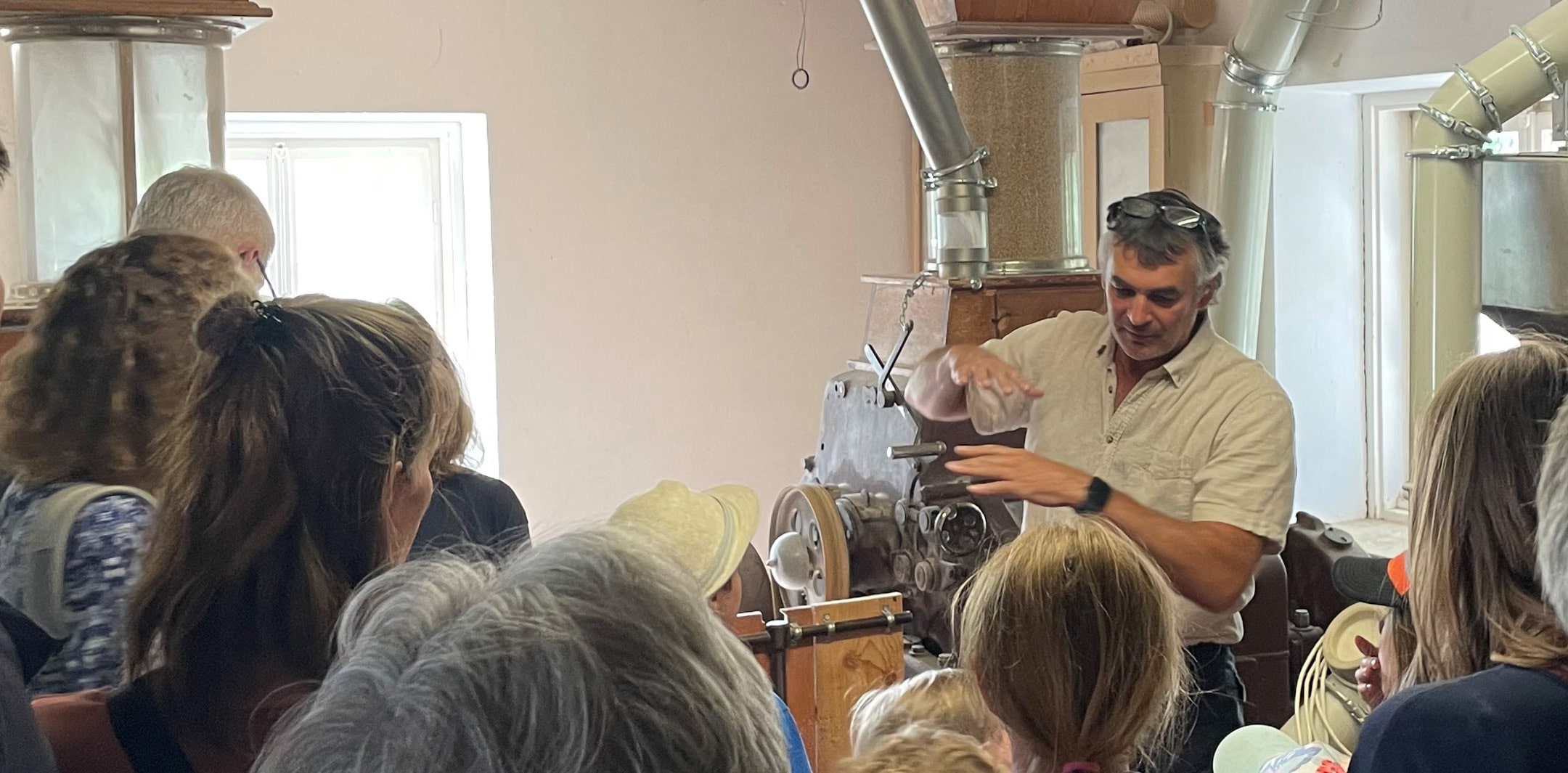Müllermeister Löffl erklärt Besuchenden, darunter Kindern, was beim Müllerhandwerk wichtig ist.